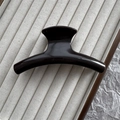 Close-up of a 11cm curved black hair claw clip with a glossy finish on textured fabric - Dark Coffee
