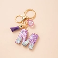 Detail of purple letter M keychain with sequins, matching tassel and golden metal clasp - Letter M