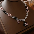 Gros plan du pendentif cristal rose et du charme chat noir sur chaîne argentée - Collier Chat Cœur
