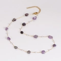 Detailed close-up of gold chain necklace with purple irregular stones and white beads - Necklace