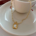Collier en titane doré avec pendentif carré en nacre blanche sur une coupelle en céramique - Collier pendentif carré en nacre dorée