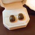 Detailed close-up of tiger eye earrings in gold frames on a beige velvet box - Trapezoid Resin