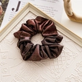 Detail showing the crinkled metallic fabric and texture of the red Christmas hair scrunchie - Basic Style / Glossy Coffee