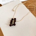 Dettaglio di una collana con nappe d'uva floccate con palline di peluche marroni e catena dorata - Collana-Caffè / Marrone