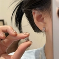 Macro detail shot of elegant silver crossed hollow hoop earrings with pavé zircon stones - Ear Buckle / Silver