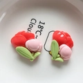 Close-up of resin flower charms with red petals and green leaves on a ceramic plate - Pink Flower