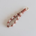 Detailed view of handmade woven daisy keychain with gold round clip and brown floral pattern - Khaki