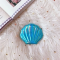 Nahaufnahme der muschelförmigen irisierenden holografischen Kosmetikspiegel auf weißem Kunstfell - Blau