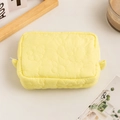 Detailed macro shot of yellow quilted flower pattern on soft padded cosmetic pouch - Yellow