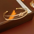 Detail of gold-plated knot bracelet with shimmering cubic zirconia on leather box - Gold