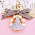 Detail of keychain featuring grey ribbon bow, pearl ring, and tassel on pink surface - Gray