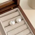 Close-up of minimalist white pearl stud earrings displayed in a wooden jewelry box - 16mm