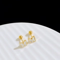 Detailopname van gouden vlinder oorknopjes met parelmoer op een gegolfd bord - Witte schelp vlinder