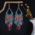 Dettaglio di orecchini colorati bohémien con nappe appesi a un ramo di legno naturale - Stile Lampadario Boho (E6329) / Multicolore