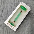 Detail of green jade facial roller in white retail box on soft plush grey background - Green Roller + Color Box