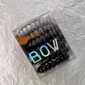 Macro view of multi-color spiral hair ties in transparent packaging box with holographic text - Gradient Black