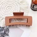 Detail of a rectangular matte hair claw clip in terracotta brown on a white coaster - Large Matte Square Claw-Orange