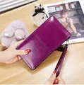 Nahaufnahme einer glänzenden dunkelvioletten langen Clutch mit passender Handschlaufe - Lila