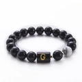 Macro view of 10mm black agate beaded bracelet featuring a marble bead and golden letter G - Letter G