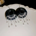 Détail de boucles d'oreilles chapeau de cowboy avec pampilles en strass sur plateau blanc - Style Crochet / Noir