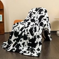 Soft flannel cow print blanket in black and white hanging on an armchair - Black and White Cow