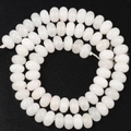 Vista detallada de cuentas de piedra blanca para hacer joyas DIY sobre fondo negro - Jade Blanco Ábaco