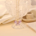 Detailopname van vlinderhanger met paarse kristallen en gouden ketting op zijde - Paars