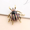 Macro view of beetle brooch showing gold plating and multicolor rhinestone inlay detail - Red AB