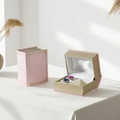 Pink book-shaped jewelry box with gold edges showing ring slots and satin interior - Plastic / Book Shaped Box (Deluxe) / Deluxe Sakura Pink