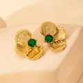 Detalle de pendientes de flor dorados con texturas radiales y gemas verde esmeralda - Verde
