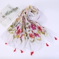 Close-up detail of white linen scarf with pink floral pattern and red tassel fringe - Style 8