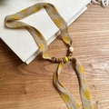Close-up detail of the yellow chiffon printed necklace featuring wooden and acrylic beads. - Necklace-Yellow