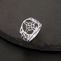 Detailed macro shot of a geometric stainless steel witch knot ring on dark slate rock - US 7 / Steel