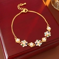 Dettaglio macro del bracciale a fiori dorati con perle e pietre su scatola in legno - Oro-Multicolore