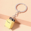 Dettaglio portachiavi a forma di mini multicooker giallo su sfondo geometrico minimalista - Resina / Forma della lavatrice / Giallo