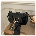 Primer plano de un bolso de hombro en charol negro con hebilla metálica dorada en forma de U - Negro