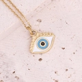 Macro shot of gold evil eye pendant with blue and white enamel on a stone surface - 11# Lake Blue