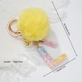 Detalle de llavero con pompón amarillo, letra L de resina y borla rosa elegante - Letra L