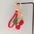Dettaglio del portachiavi a ciliegia con foglie smaltate, strass e cinturino in pelle - Rosso + Cordino a Cuore