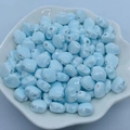 Macro shot of light blue shell-shaped ceramic beads in a white decorative tray - 12mm / Light Lake Blue
