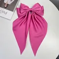 Large bright pink satin bow hair clip with long streamers on a white display surface - Lotus Pink