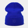 Detailed close-up of dark blue ribbed knit beanie featuring white sun embroidery - Blue
