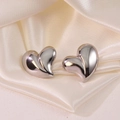 Minimalist silver heart stud earrings with glossy finish on cream silk fabric - Silver