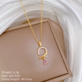 Macro-opname van gouden hanger met kristallen ring, roze druppelsteen en sierlijke strik - Titanium Stalen Ketting Koperen Hanger / Ketting (D245)