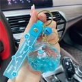 Sky blue unicorn shell keychain with silicone strap and gold bell on a car background - Blue-Shell Unicorn