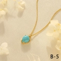 Detail of 18K gold-plated cuban chain with blue teardrop gemstone pendant on beige silk - Turquoise