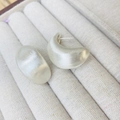 Macro di orecchini a mezzaluna in argento opaco spazzolato su una scatola di tessuto beige - Orecchini a Bottone Spazzolati a Goccia