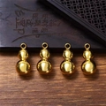 Four polished golden metal gourd pendants with hanging rings on a wooden desk background - Solid Gourd