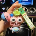 Pink popping eyes frog keychain with blue bell and silicone strap on car background - Stress Relief Pop-Eye Frog with Bell / Pink