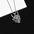 Gros plan d'un collier avec pendentif masque de démon Prajna sur une pierre texturée - Masque Hannya en Argent Vintage